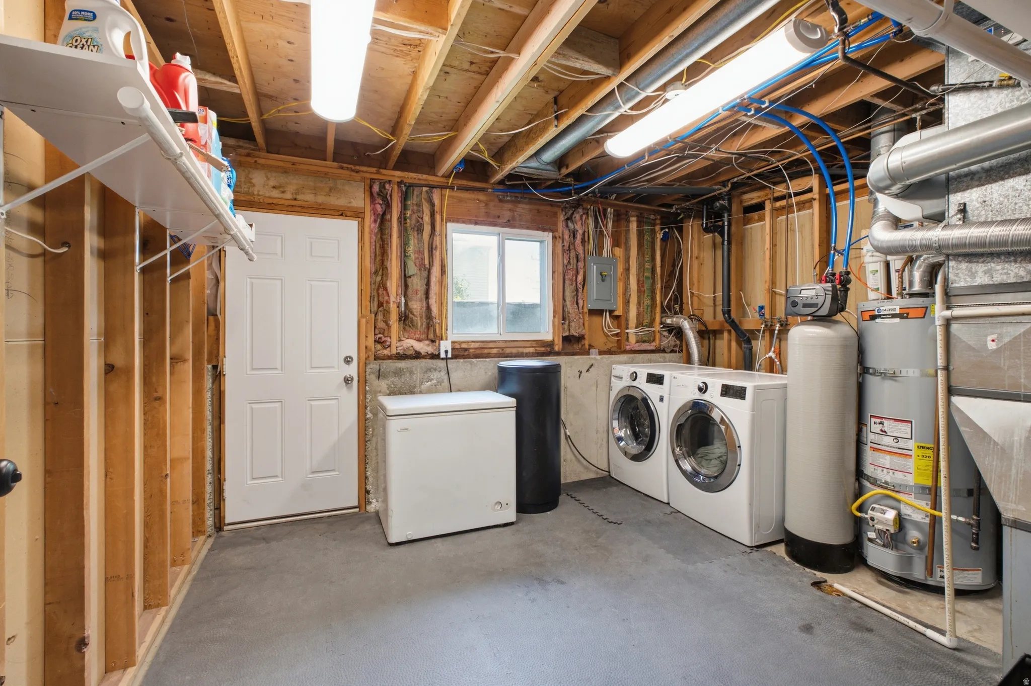 Utility area featuring a concrete floor, exposed ceiling joists, and a window for natural light