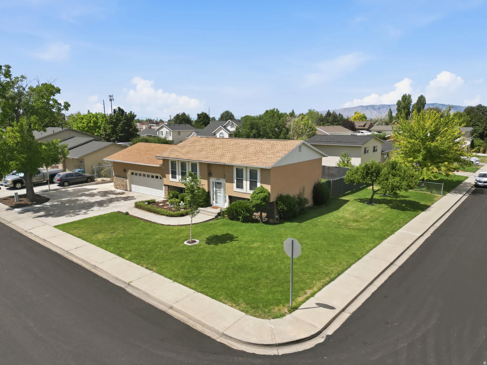 Corner lot property featuring a two-story residence with a tan exterior and a brown shingle roof