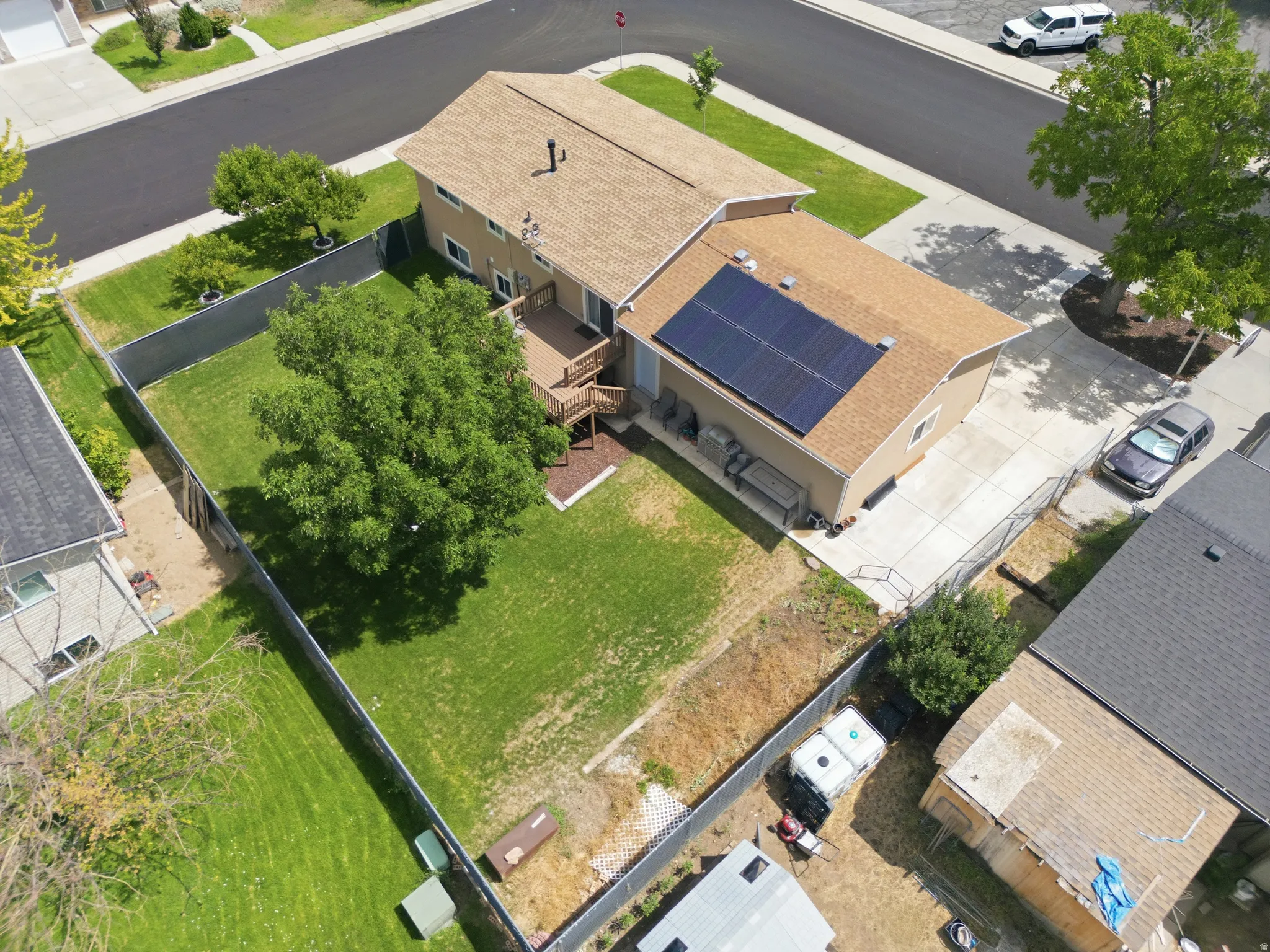 Two-story home with a fenced backyard, mature landscaping, and a wood deck