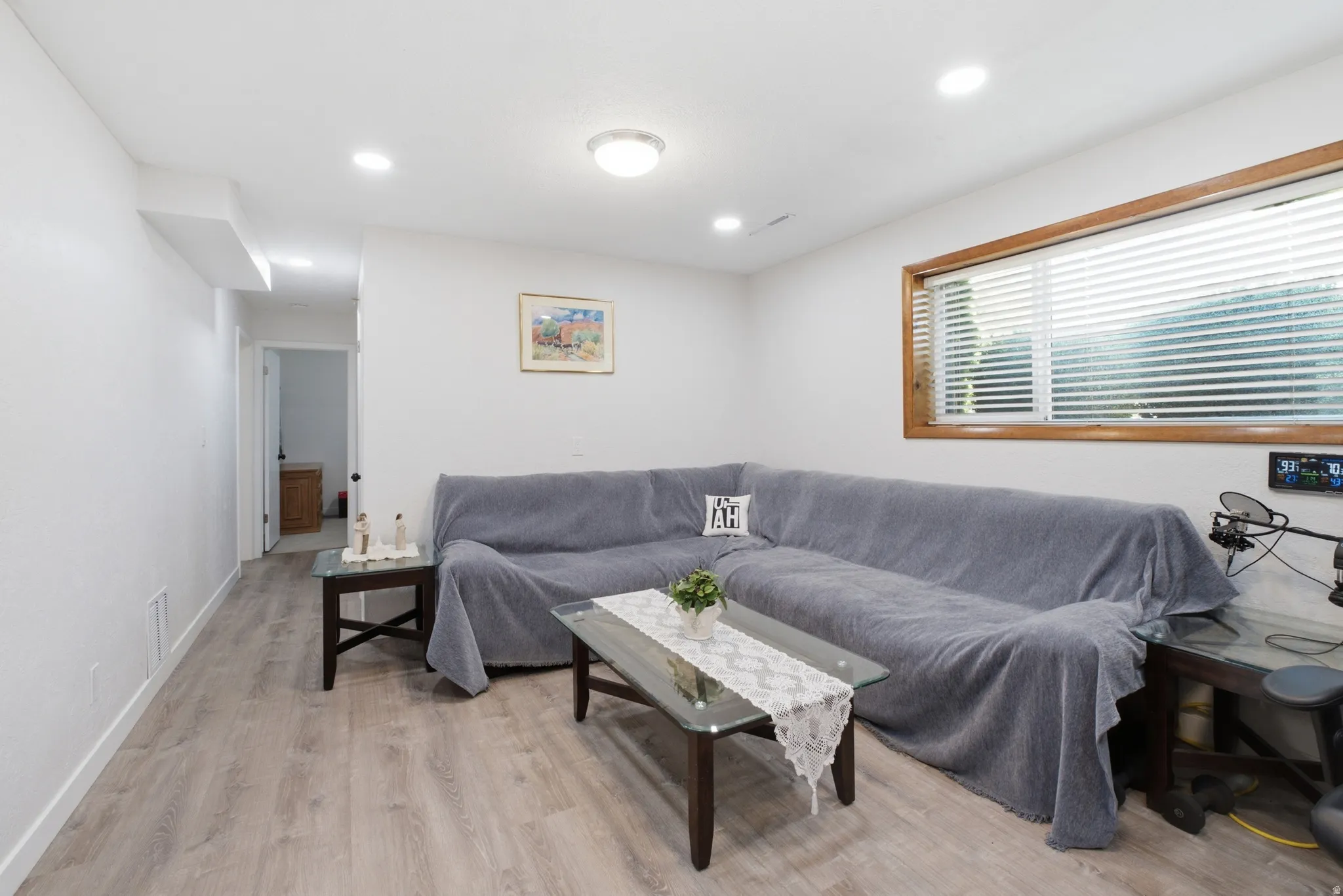 Spacious room featuring wood-finish flooring, recessed lighting, and a window with blinds