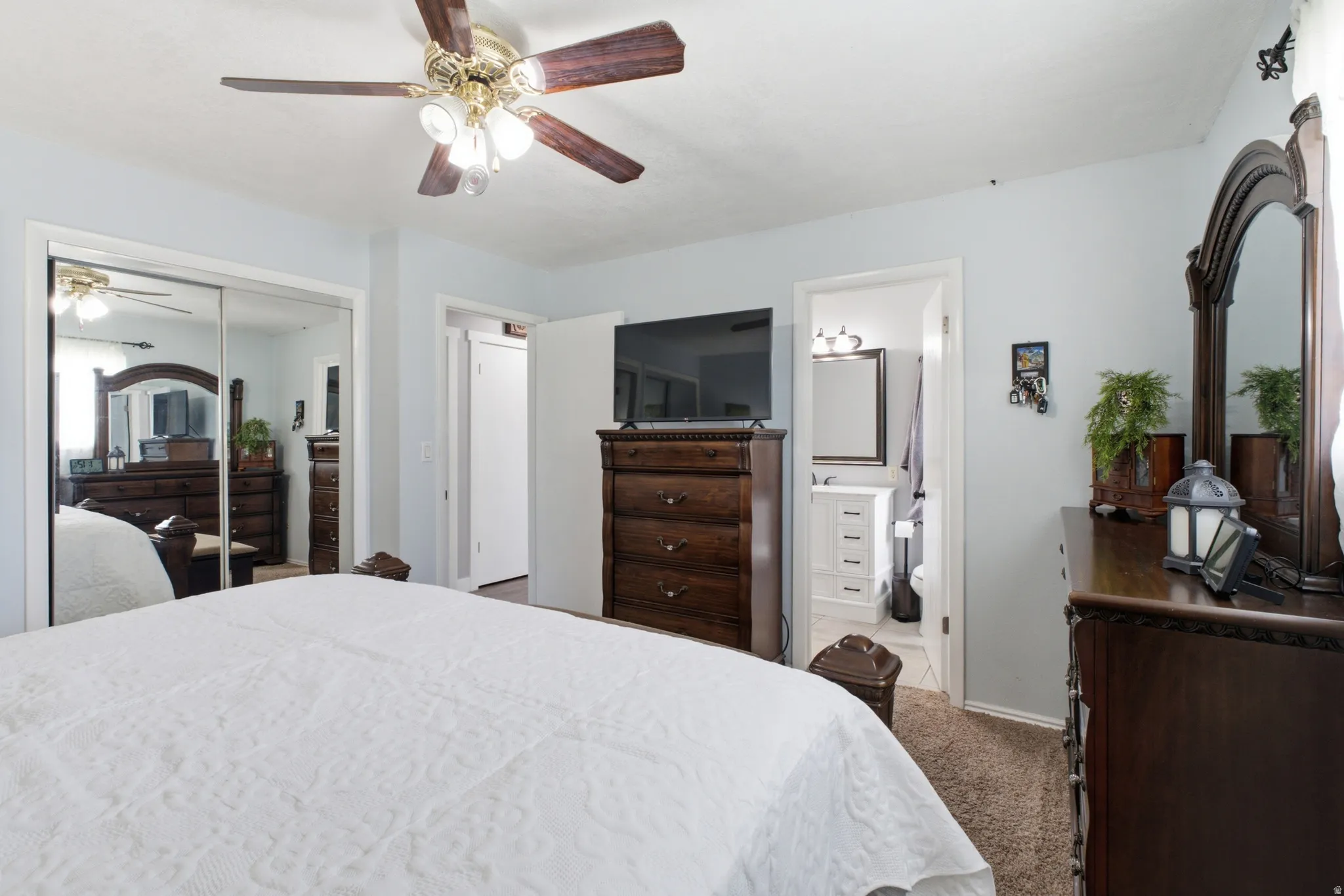 Carpeted room with a ceiling fan light fixture, mirrored closet doors, and light blue wall color