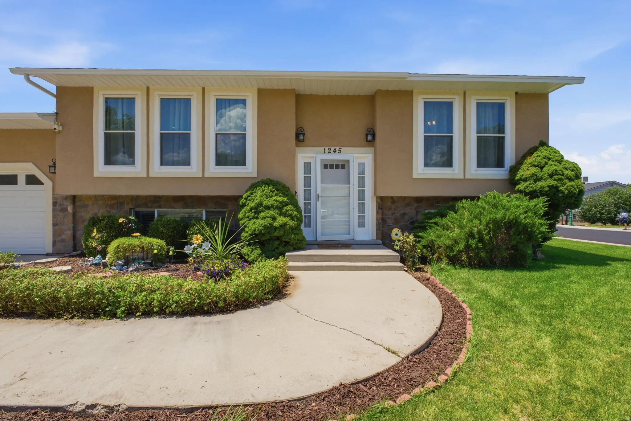 Front exterior featuring a stucco finish with stone accents and white window trim