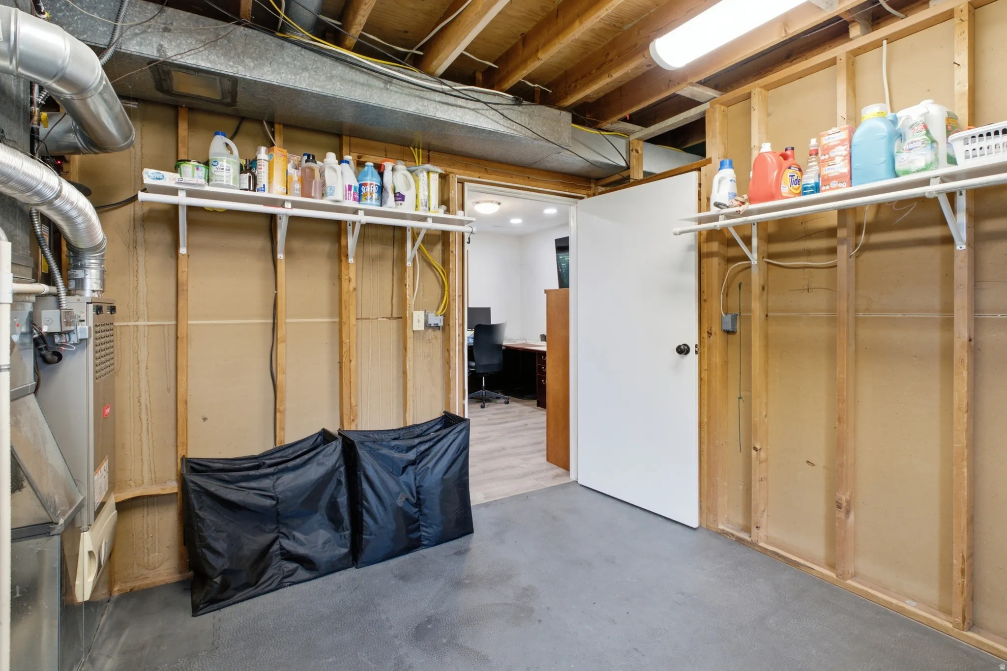 Utility area featuring an exposed ceiling, concrete flooring, and a furnace unit