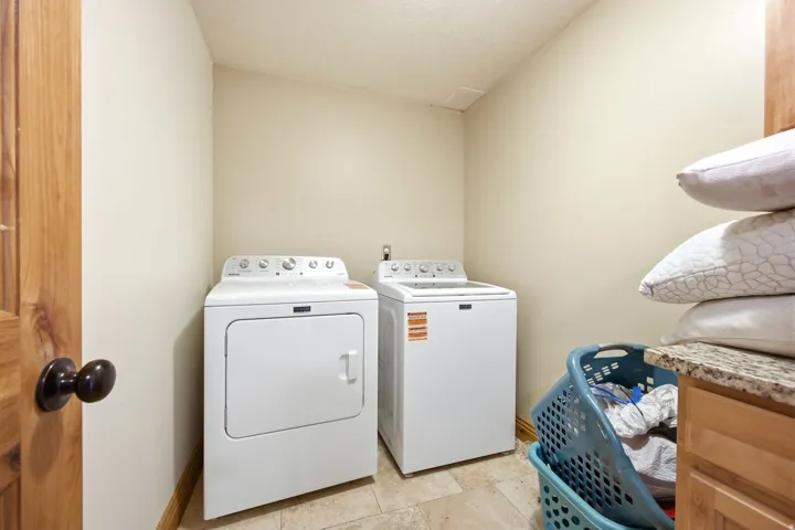 Main home - Dedicated laundry area featuring a washer and dryer, tile flooring, and light-toned walls