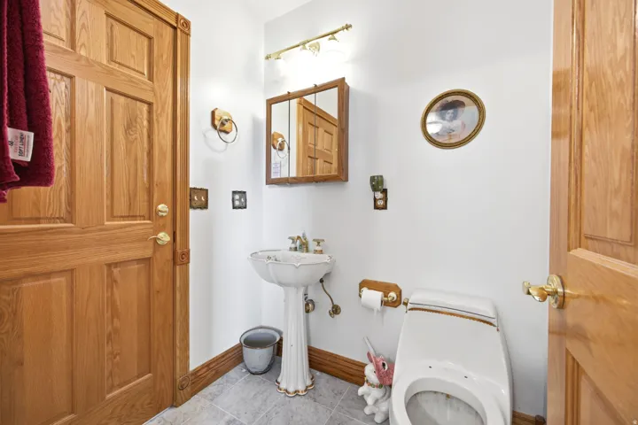 Main Home - Pedestal sink with decorative base, wall-mounted mirror cabinet, and warm wood-finish trim