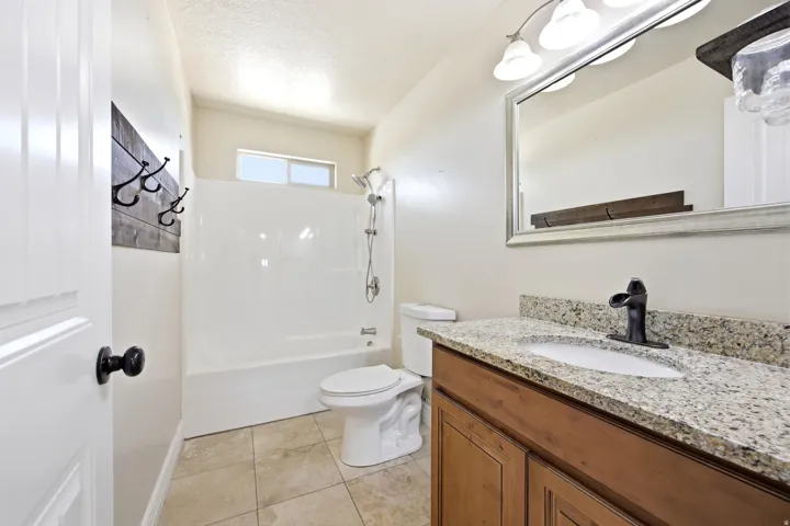ADU - Bathroom featuring a wood-finish vanity with a light granite countertop and under mount sink