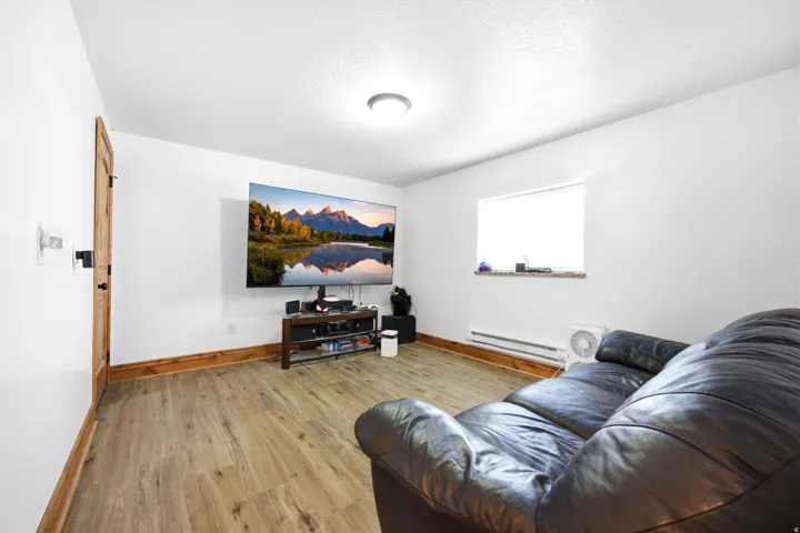 Main home - Spacious room featuring wood-finish flooring, white walls, and a recessed ceiling light