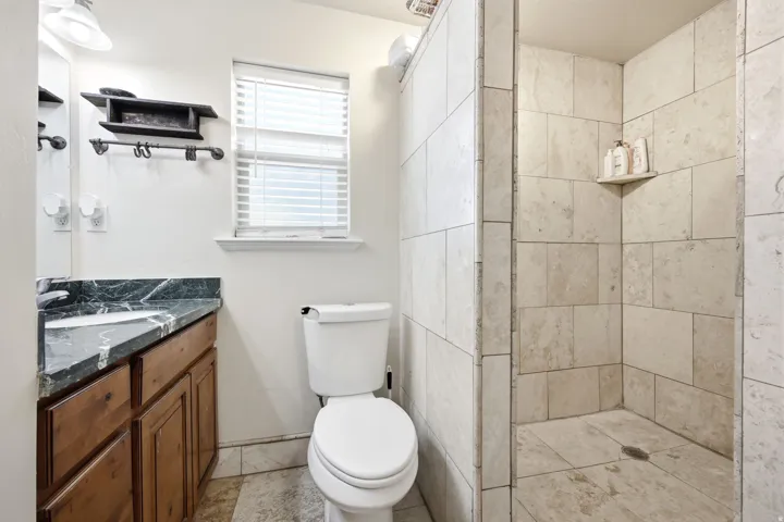 Walk-in shower with natural stone-look tiling and built-in shelf