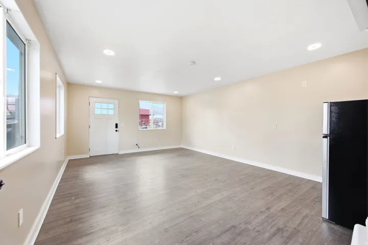 Studio ADU - Open-concept living area with wood-finish flooring, recessed lighting, and multiple windows
