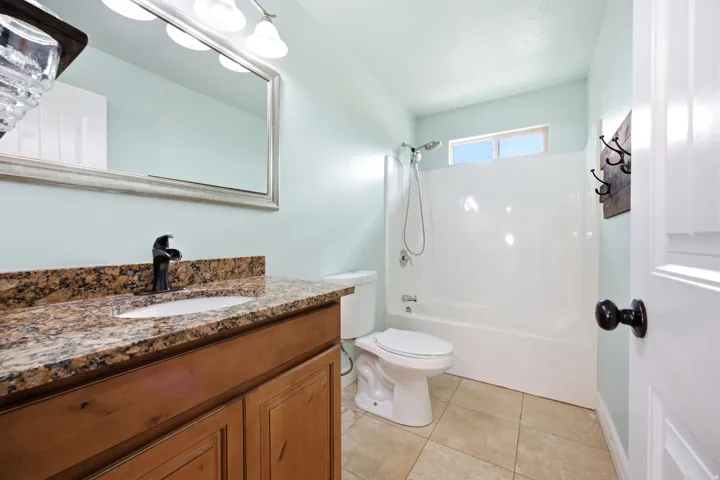 ADU - Bathroom featuring a wood vanity with a granite countertop, under mount sink, and black faucet