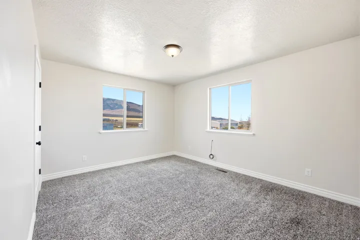 ADU - Spacious room featuring neutral carpeting, white walls, and two windows providing expansive outdoor scenery
