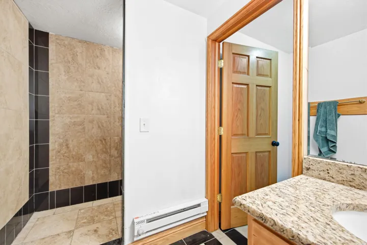 Walk-in shower featuring light-toned and dark-toned tilework
