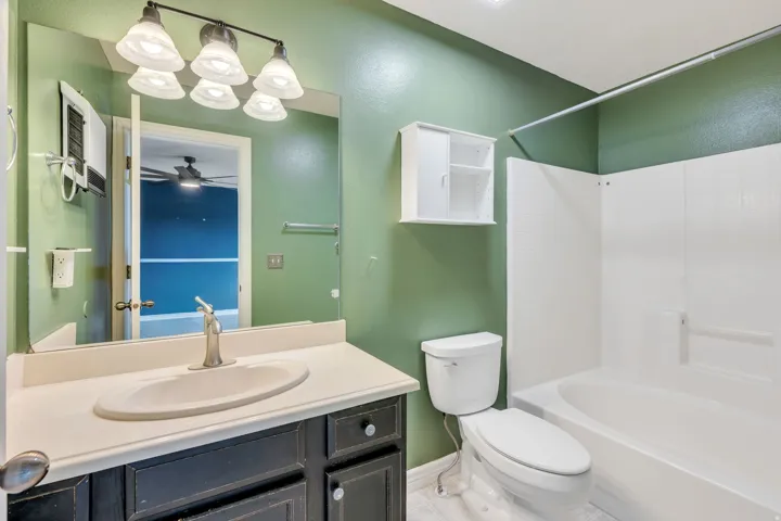 Full bathroom featuring a single vanity with a solid surface countertop, an undermount sink, and a brushed nickel faucet