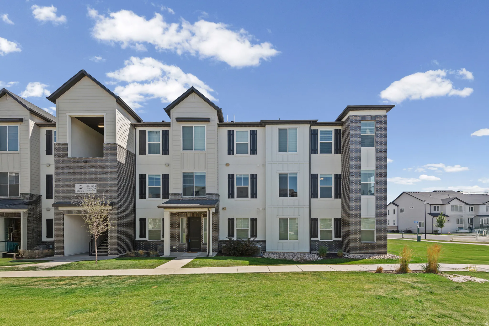 Modern townhome-style building featuring vertical siding accents and dark brick detailing