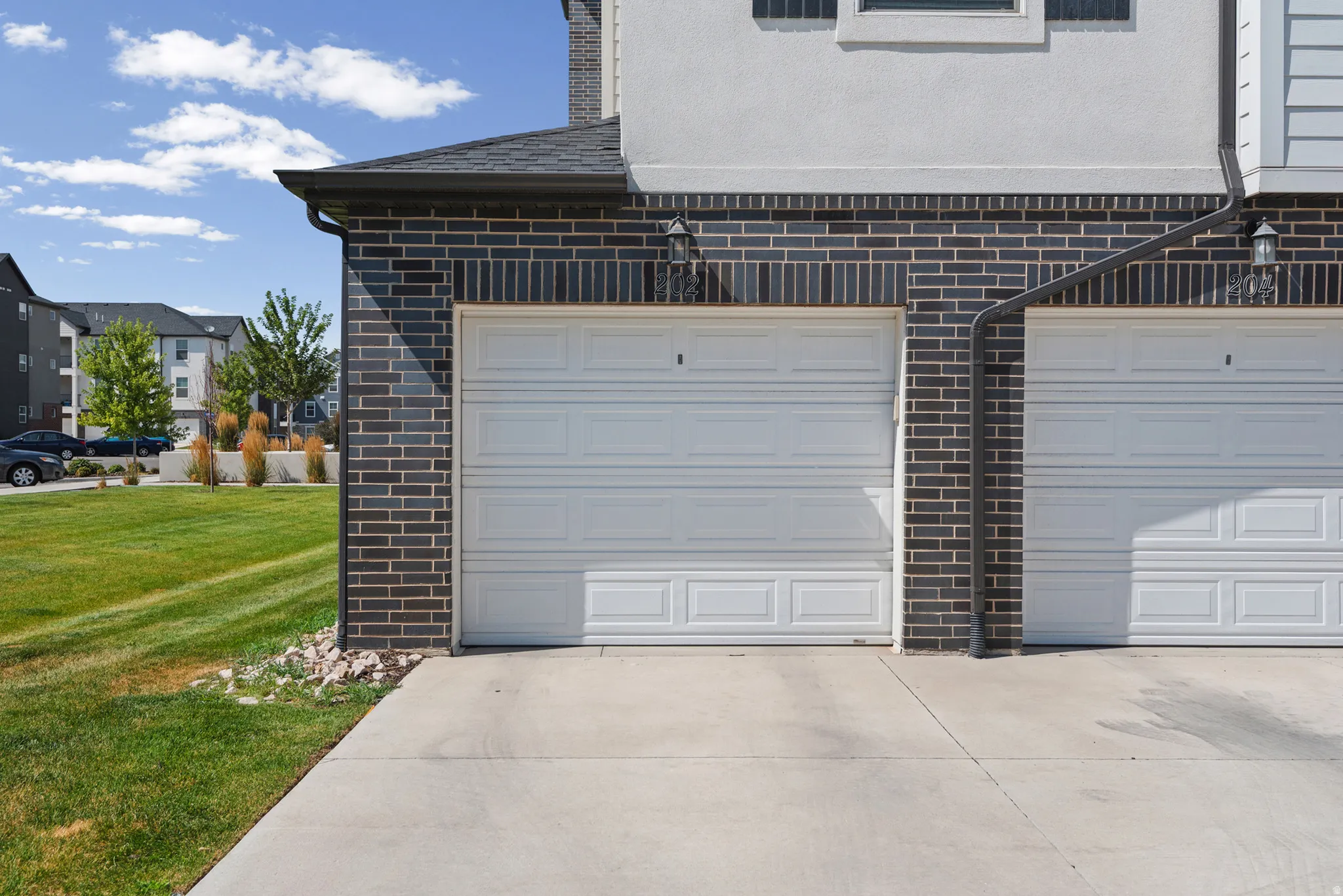 Exterior featuring dark brick siding and white panel garage doors