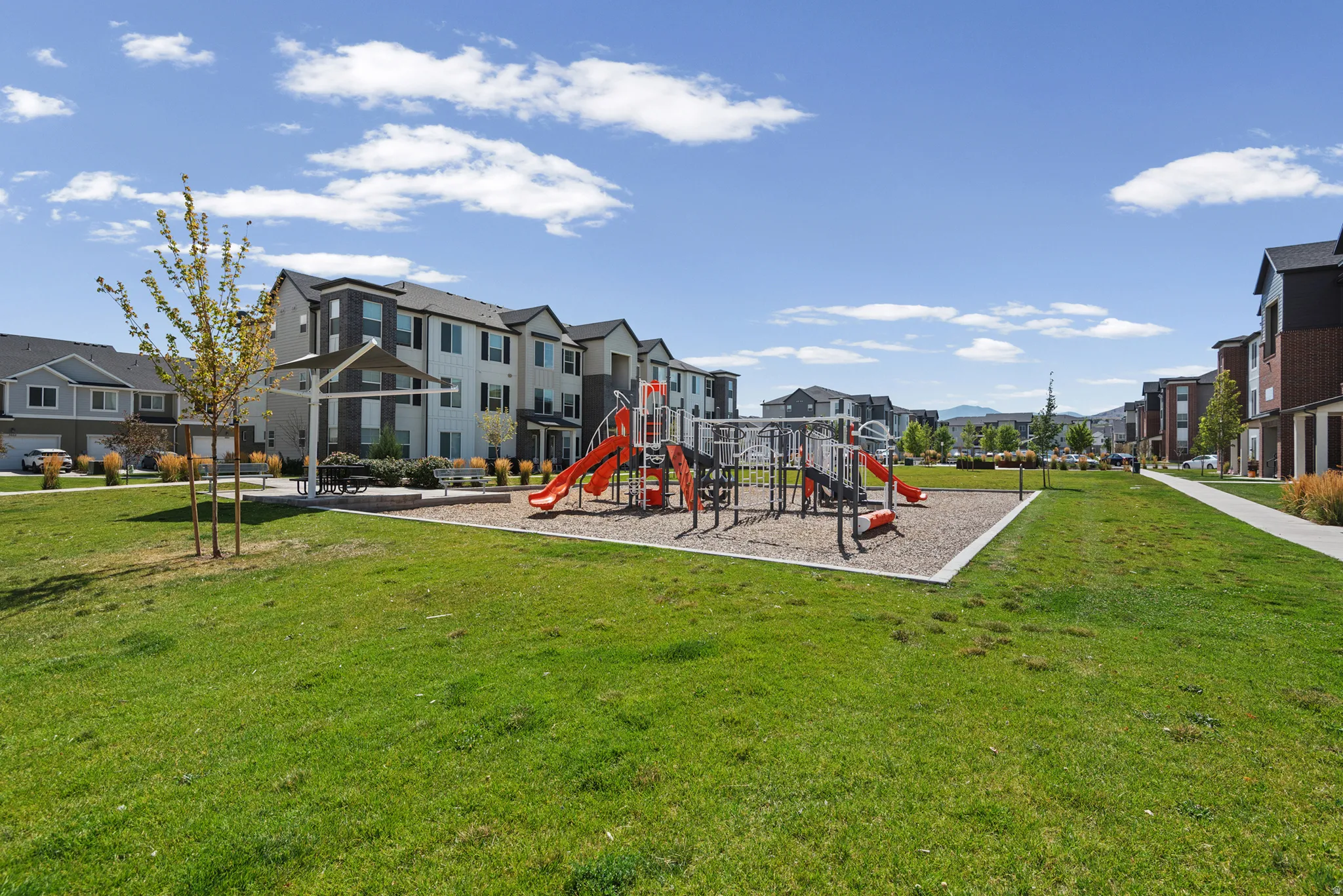 Community green space featuring a playground with slides, swings, and climbing structures