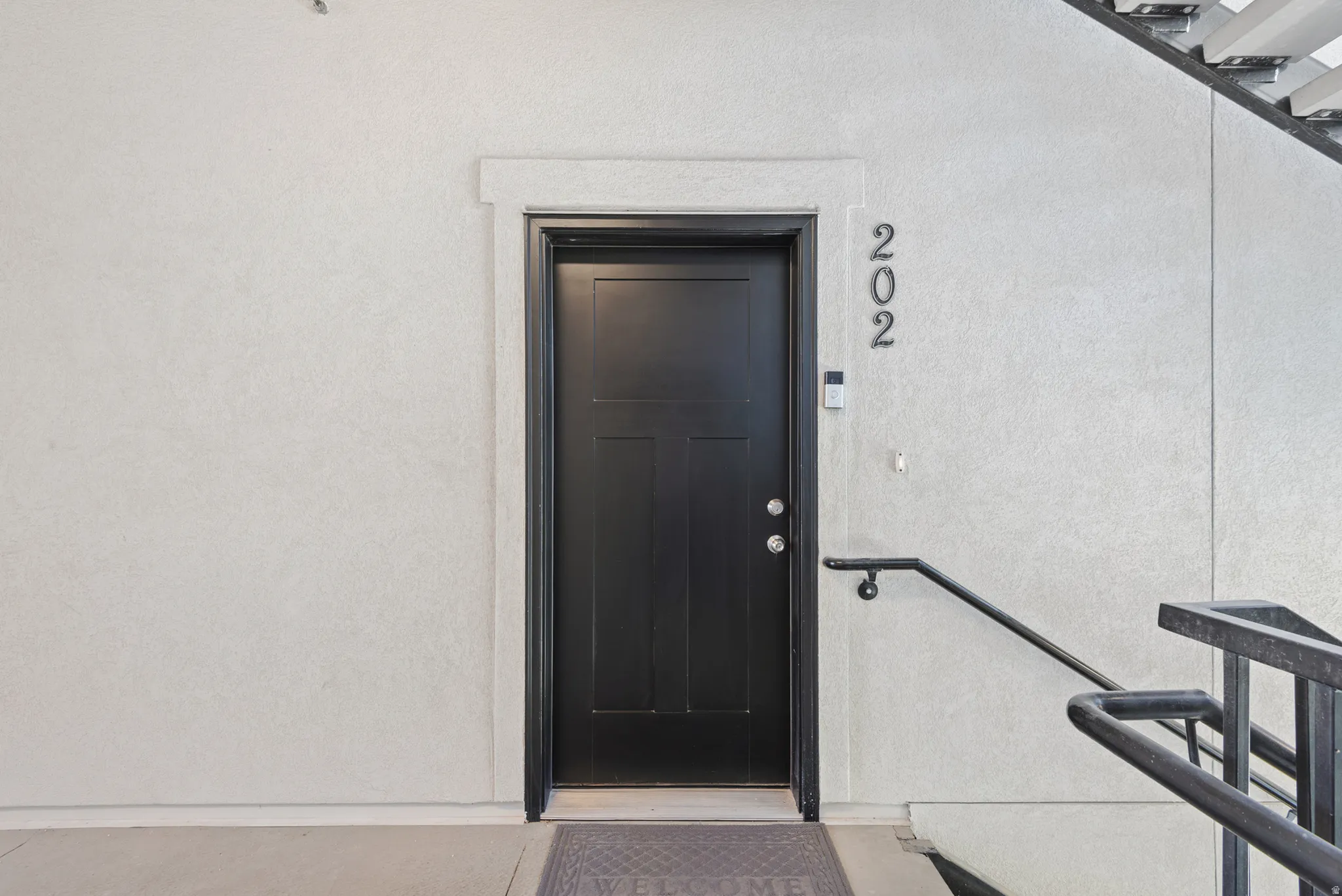 Black paneled entry door with chrome hardware, featuring white trim and textured wall finish