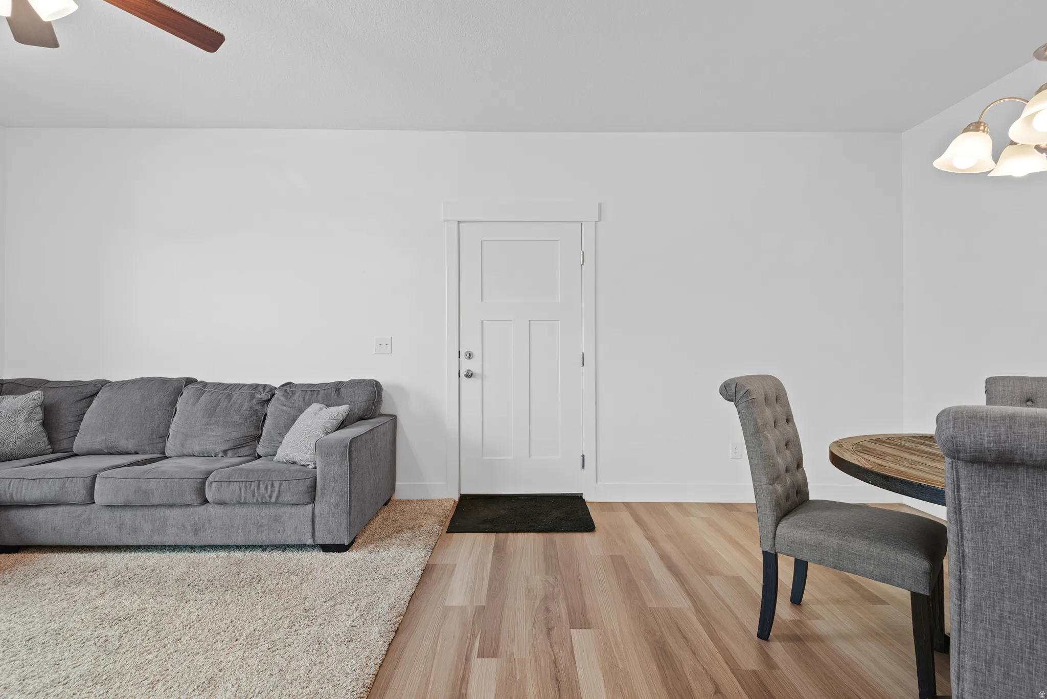 Open-concept living space featuring wood-finish flooring, a contemporary ceiling fan, and a chandelier-style light fixture