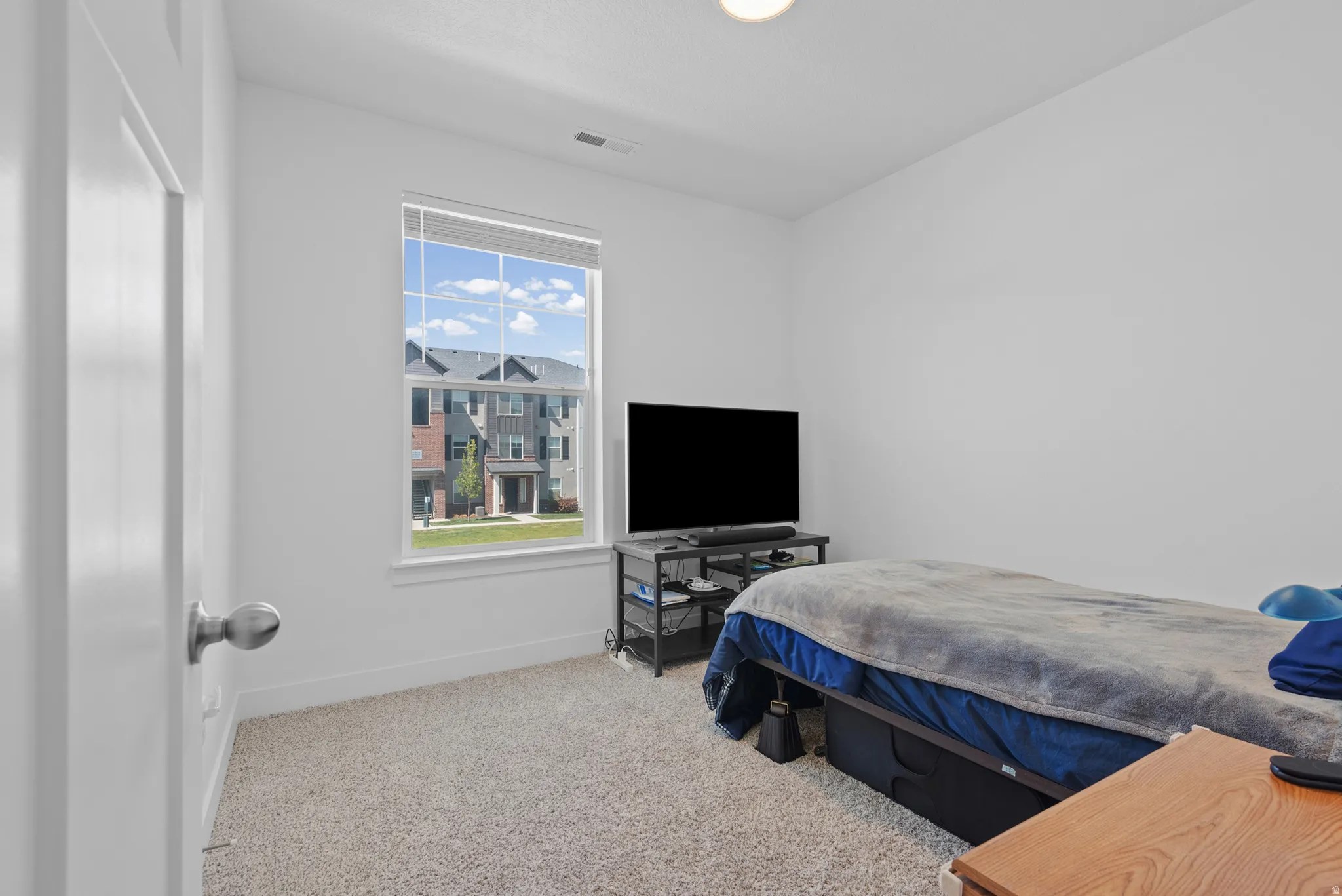 Carpeted room featuring a single window, white walls, and a ceiling-mounted light fixture