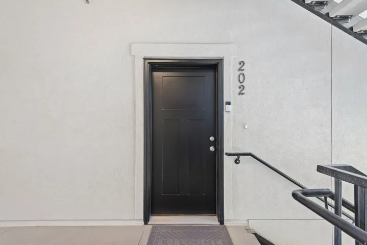 Black paneled entry door with chrome hardware, featuring white trim and textured wall finish