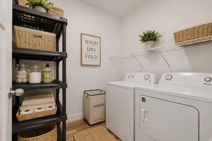 Dedicated laundry area featuring a white washer and dryer, wire shelving, and wood-finish flooring