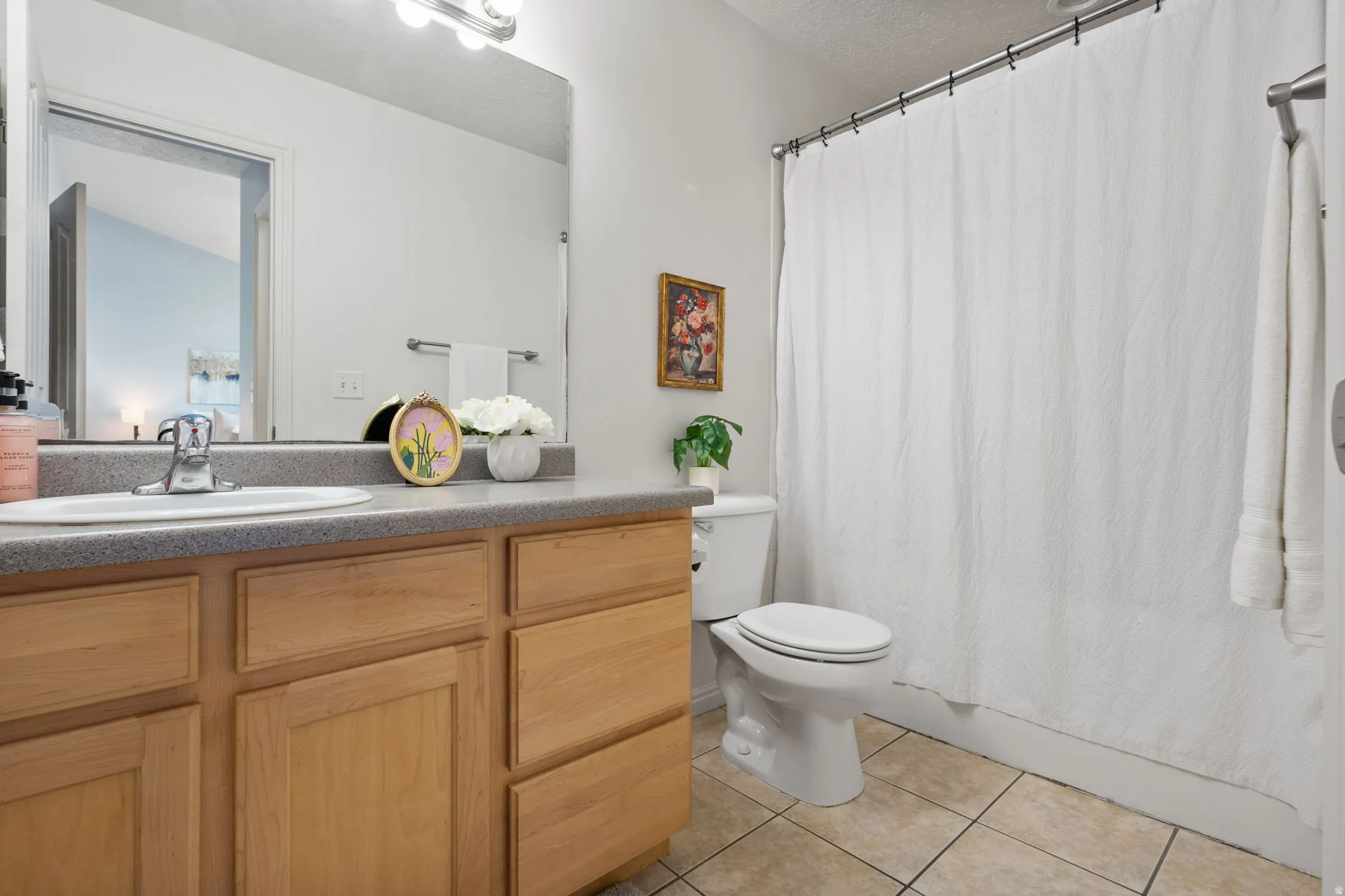 Bathroom vanity featuring wood-finish cabinetry, a light gray countertop, and an integrated white sink with a chrome faucet