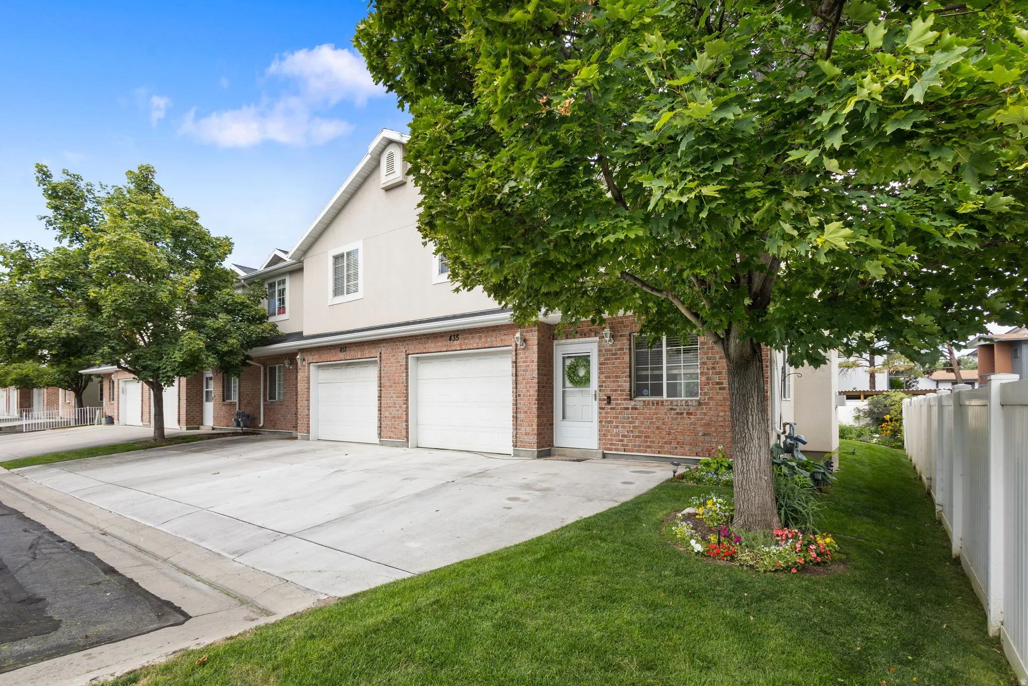 Multi-story residence featuring a brick facade, dormer windows, and attached garages