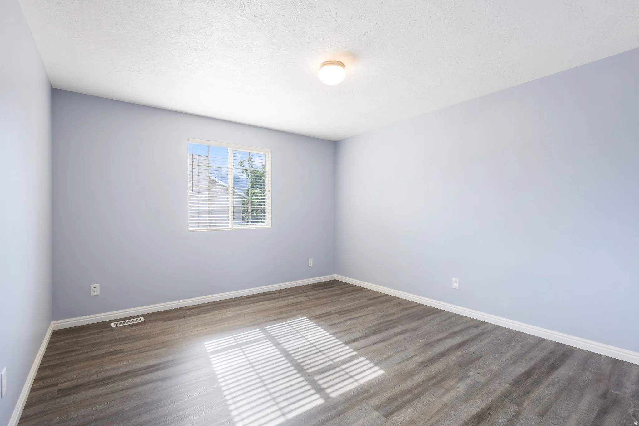 Light blue walls featuring a single window with blinds