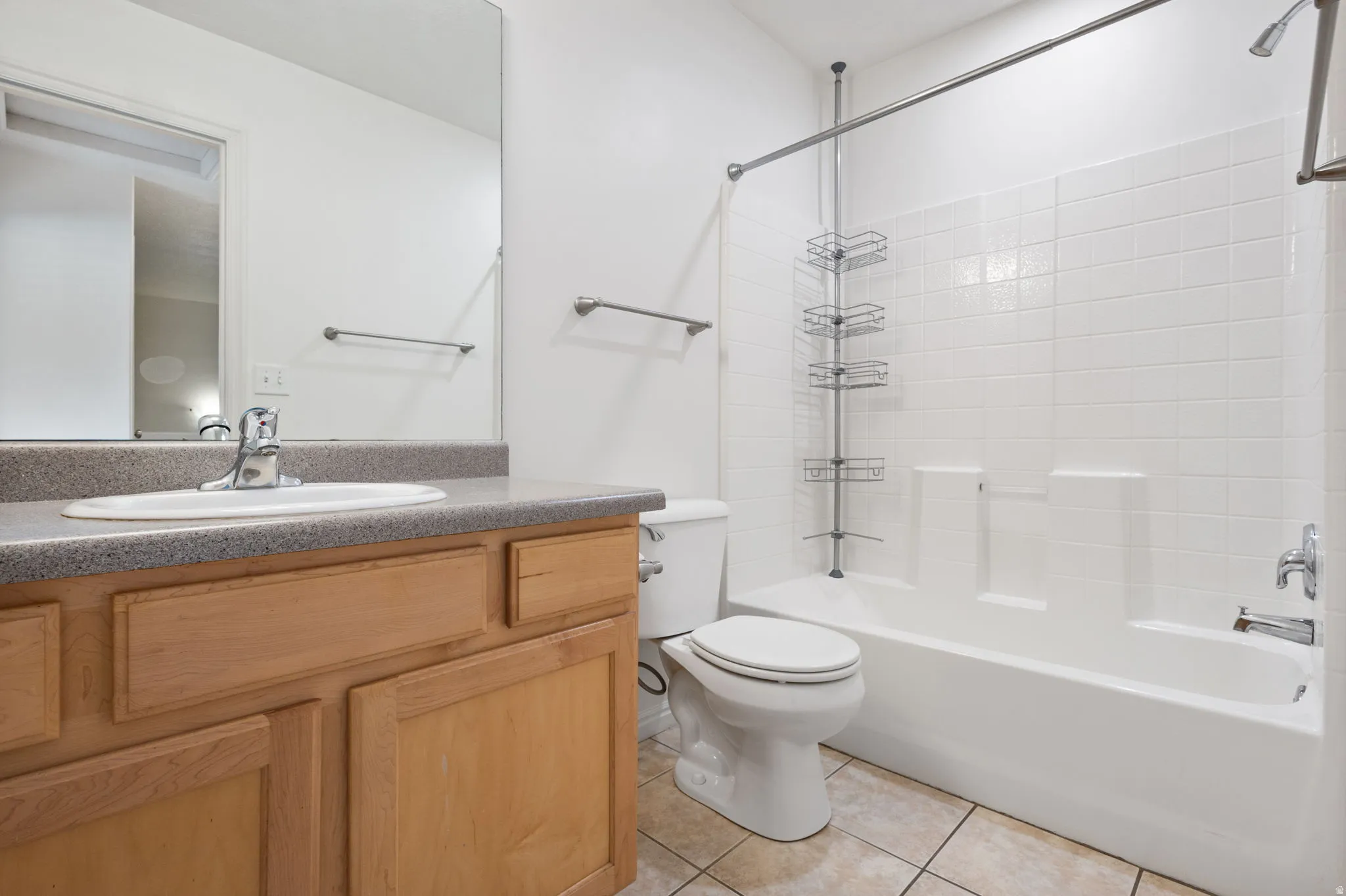 Full bathroom featuring a single vanity with wood-finish cabinetry, a built-in toilet, and a combined shower-tub unit with white subway tile surround