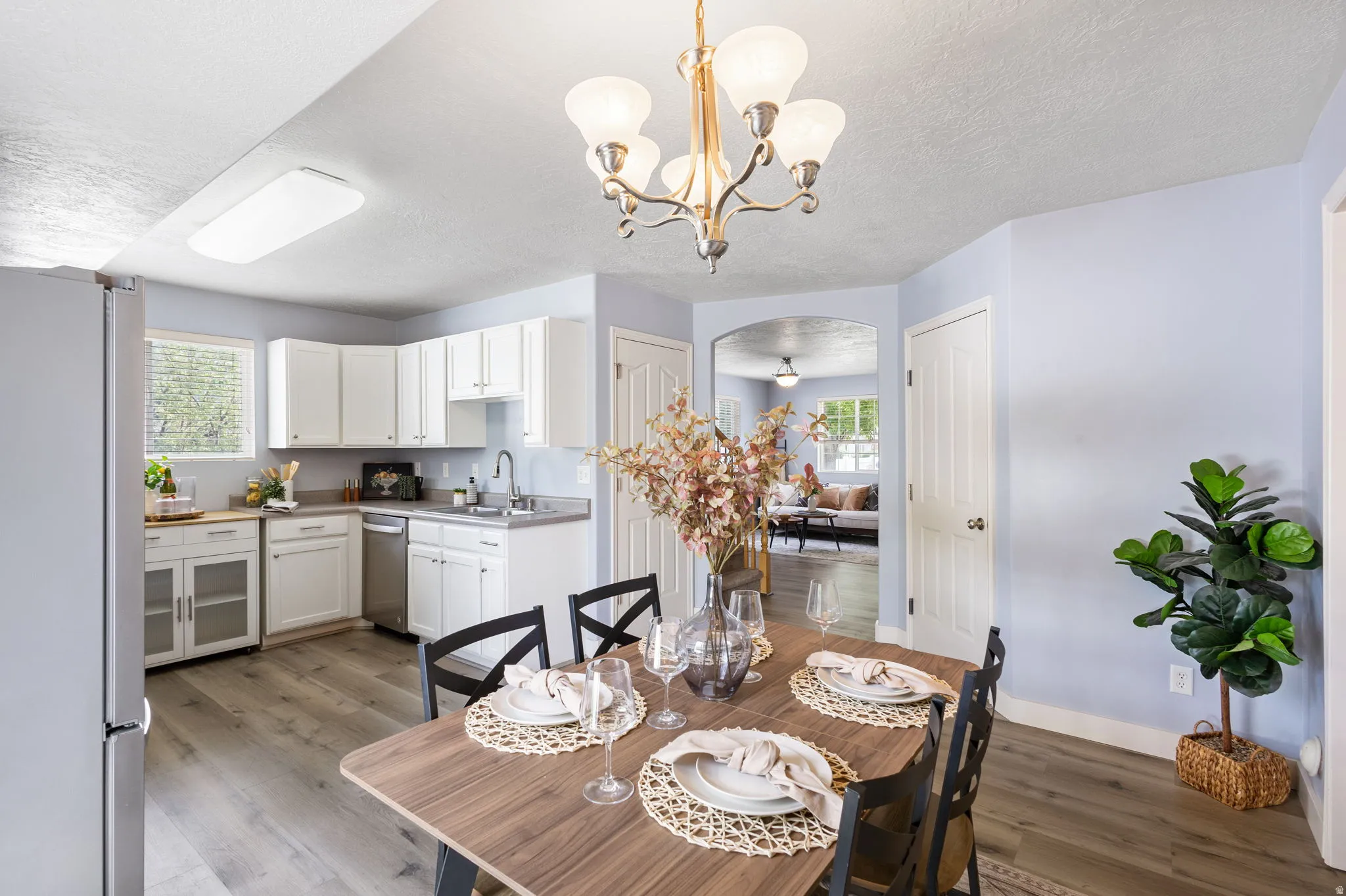 Dining area featuring wood-finish flooring, a contemporary chandelier, and an arched doorway