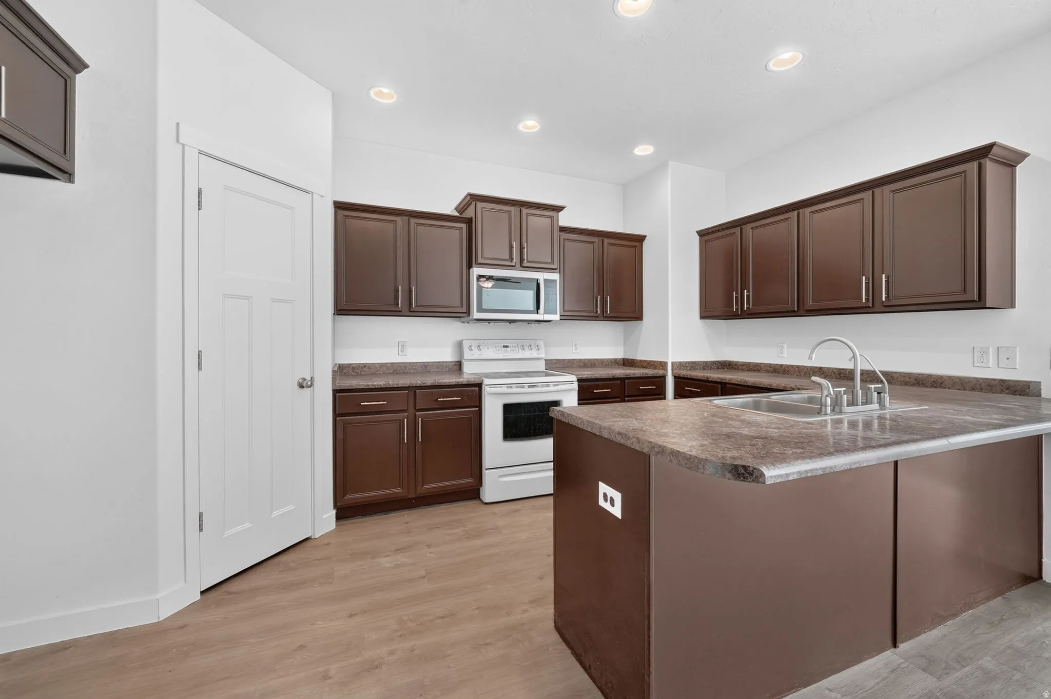 Kitchen featuring wood-finish flooring, recessed lighting, and a white paneled door