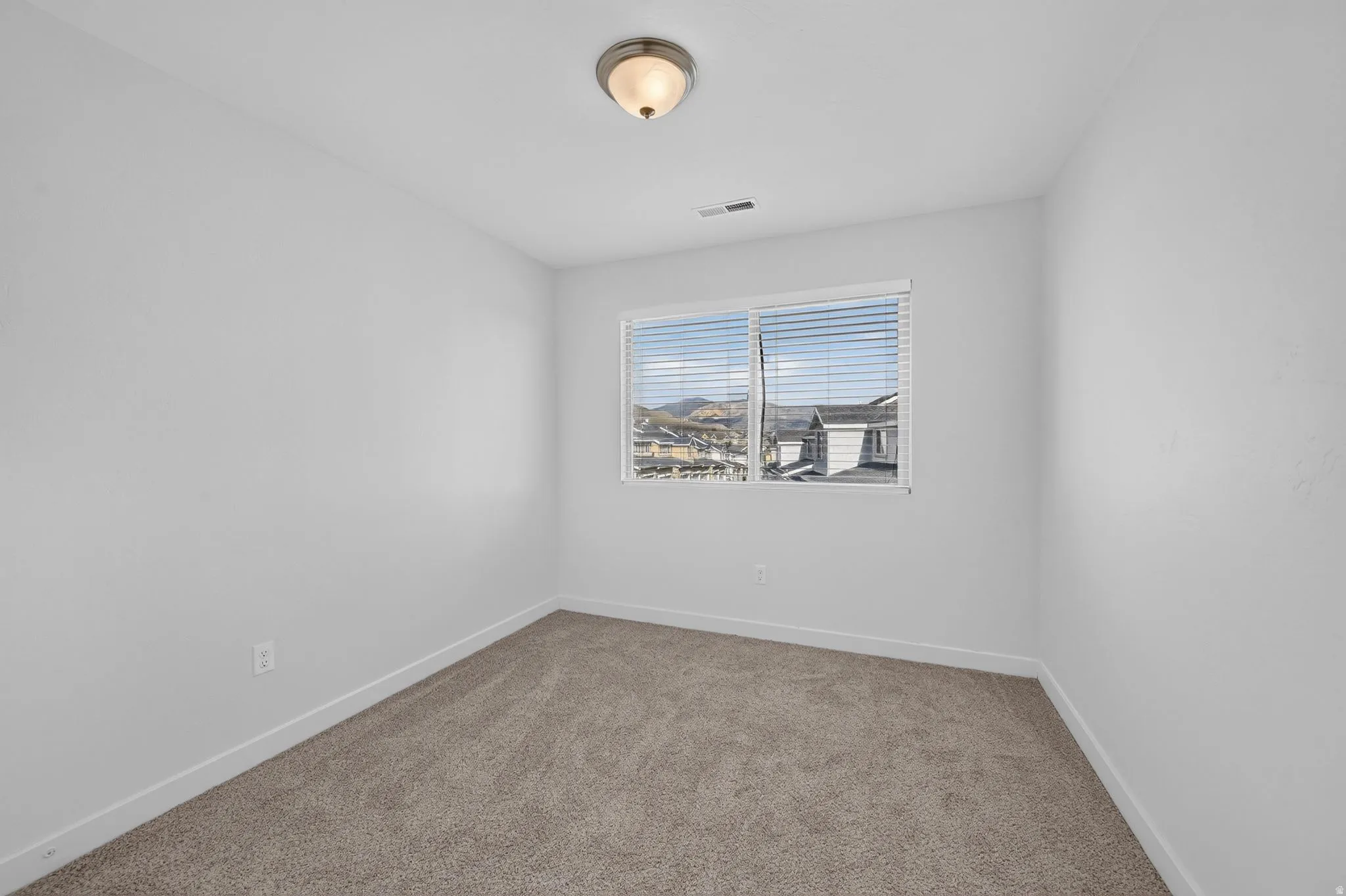 Bedroom featuring neutral carpeting, white baseboards, and a window with horizontal blinds