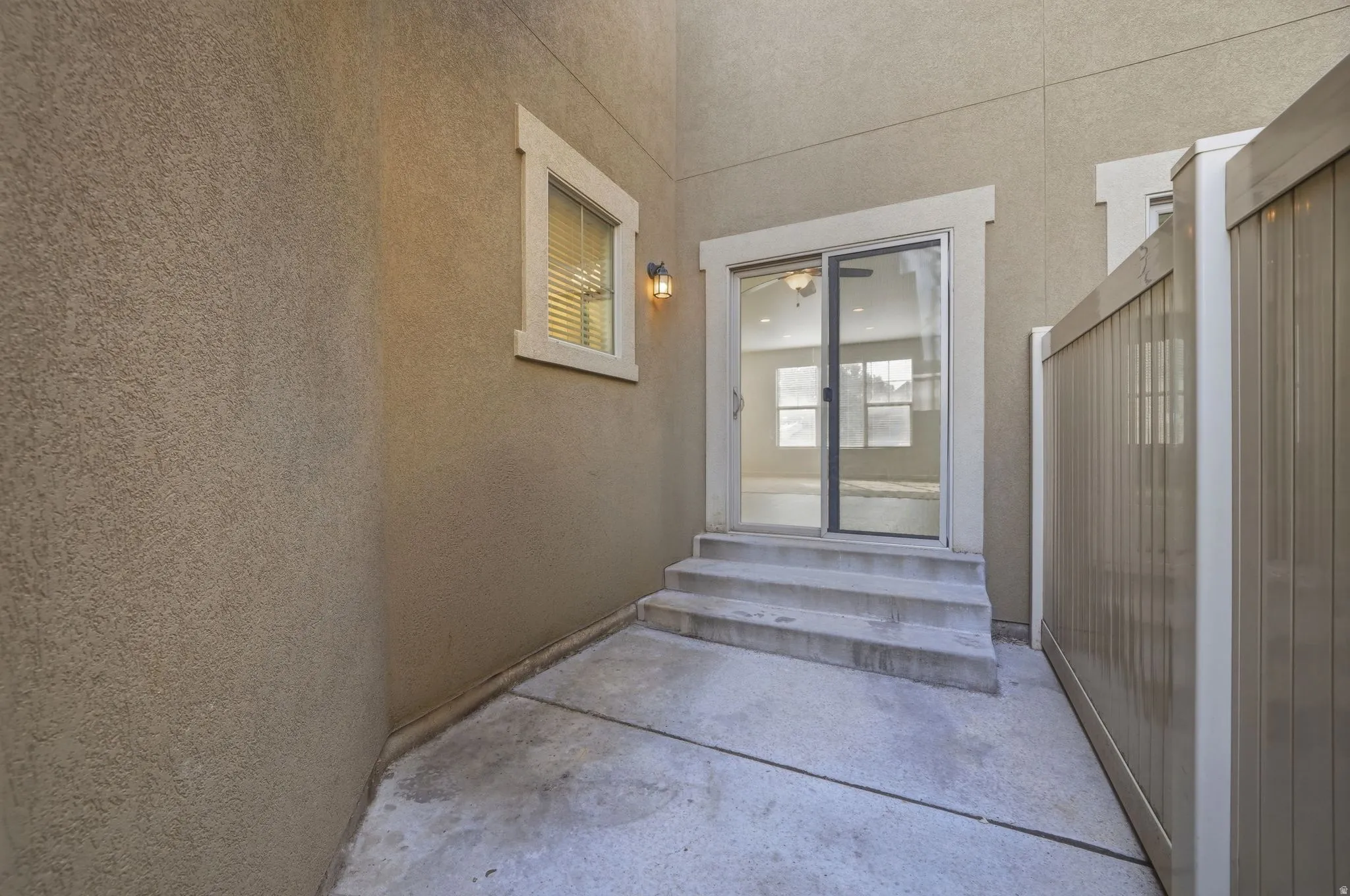 Private exterior patio featuring concrete flooring and a privacy fence