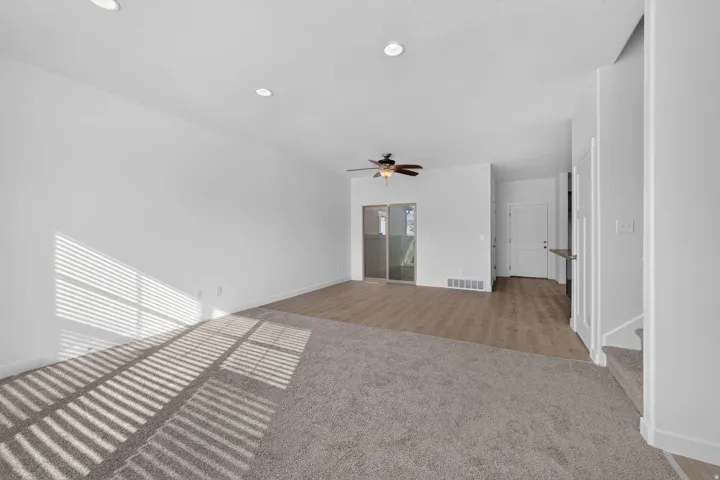 Spacious room featuring a mix of plush carpeting and wood-finish flooring, recessed lighting, and a ceiling fan