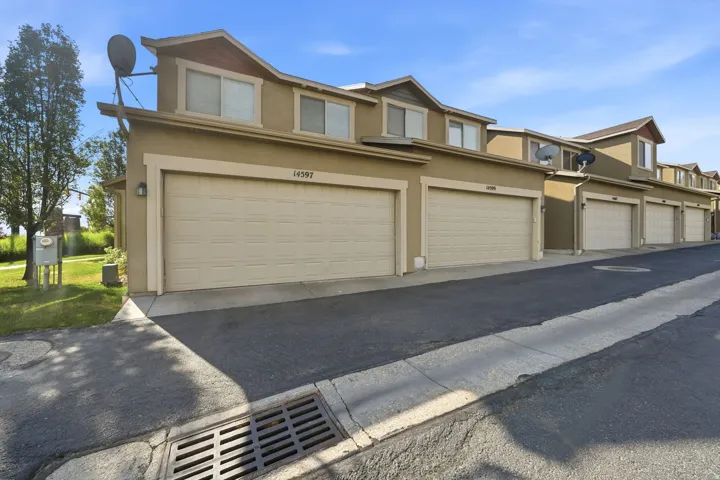 Townhome exterior featuring tan stucco siding and dormer windows