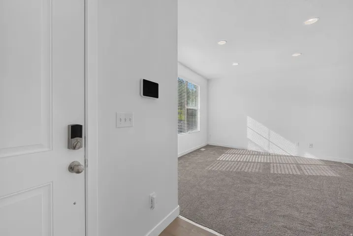 Entryway featuring a white paneled door with smart lock, light wood-finish flooring, and a wall-mounted smart home control panel