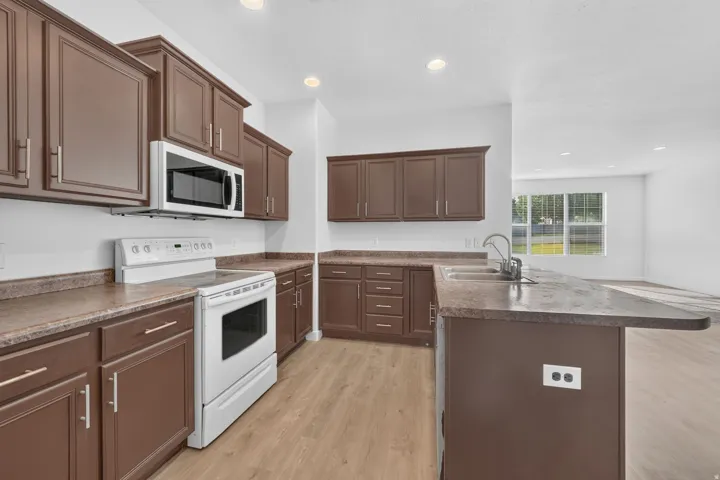 Kitchen featuring dark wood-finish cabinetry, light-toned countertops, and wood-finish flooring