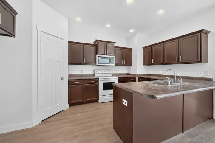 Kitchen featuring wood-finish flooring, recessed lighting, and a white paneled door