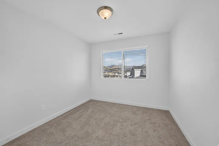 Bedroom featuring neutral carpeting, white baseboards, and a window with horizontal blinds