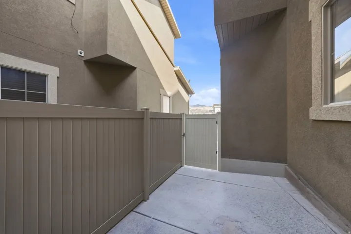 Private side yard featuring a durable privacy fence, a functional gate, and a concrete patio surface