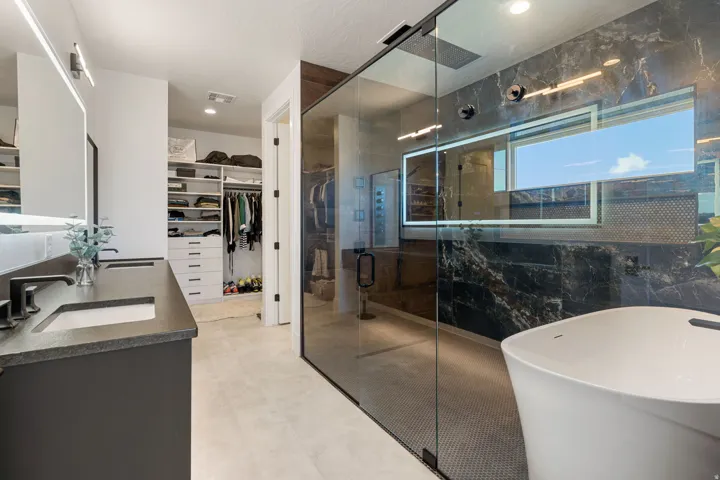 Primary bathroom featuring a wetroom, dual vanity with undermount sinks, and a large custom closet with built-in shelving