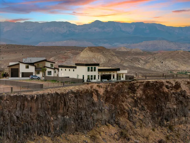 Modern cliffside residence featuring a flat roofline, extensive windows, and a mountain backdrop