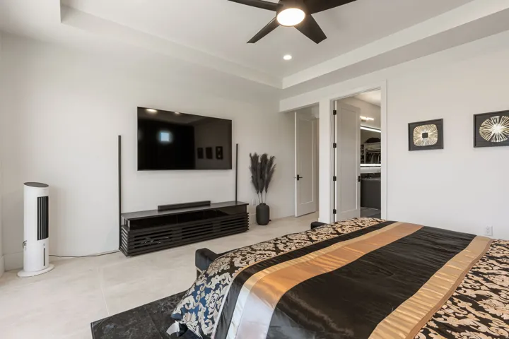 Tray ceiling with recessed lighting and a ceiling fan in primary bedroom