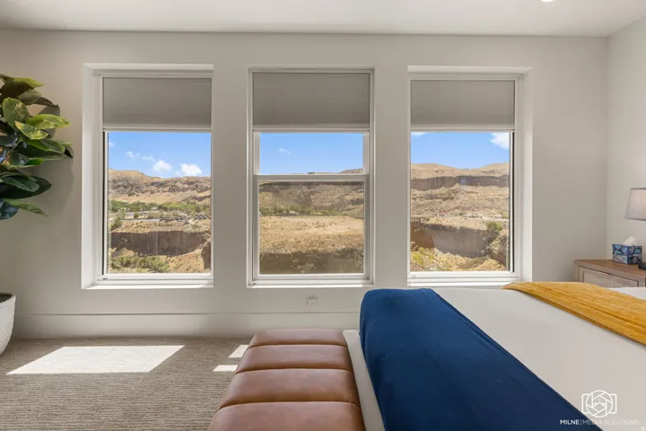 ADU bedroom with three large windows with roller shades frame expansive desert and mountain scenery
