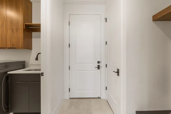 Laundry area featuring wood-finish upper cabinetry, a utility sink with a matte black faucet, and a quartz-finish countertop