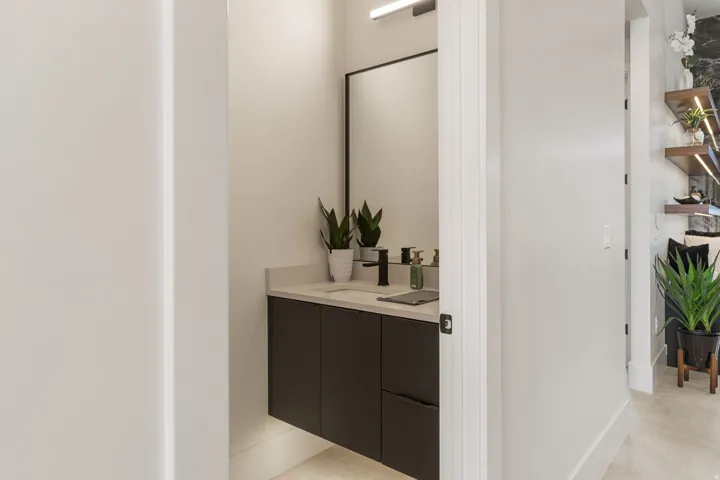 Modern vanity with dark cabinetry, light countertop, and black fixtures