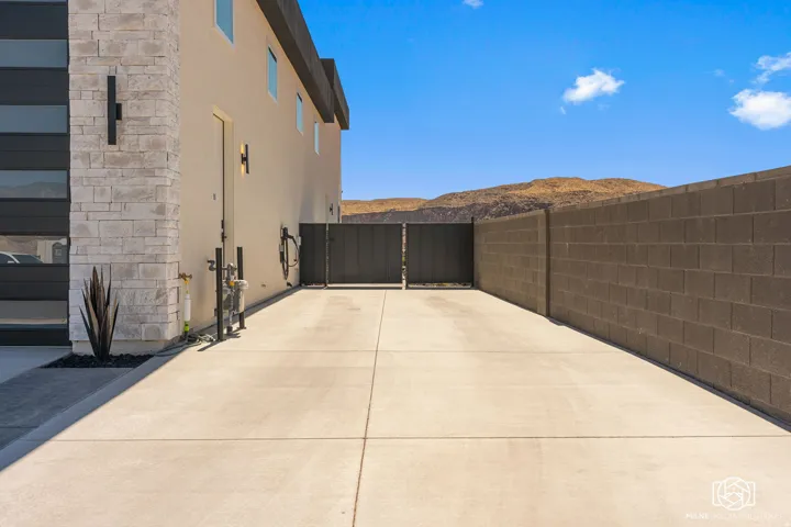 Expansive ADU concrete driveway bordered by a privacy block wall and a modern stucco exterior with stone accents