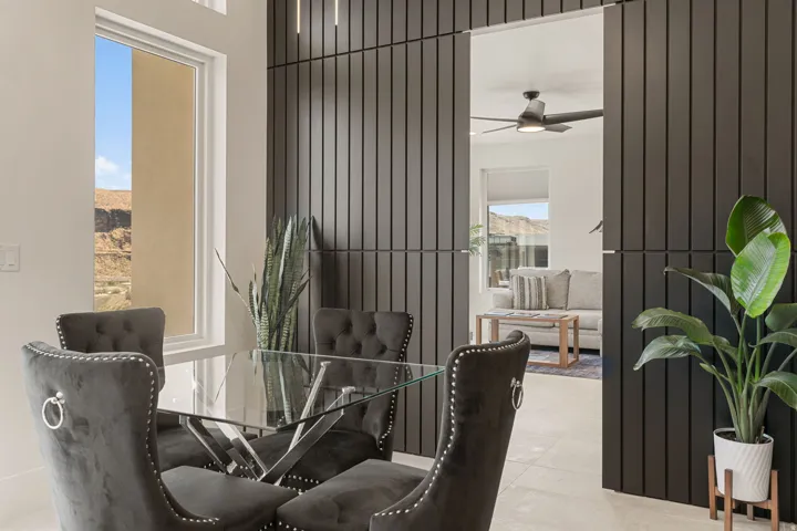 Dining area featuring a large window, dark slatted accent wall, tiled flooring, recessed ceiling lighting, and hidden door to the ADU
