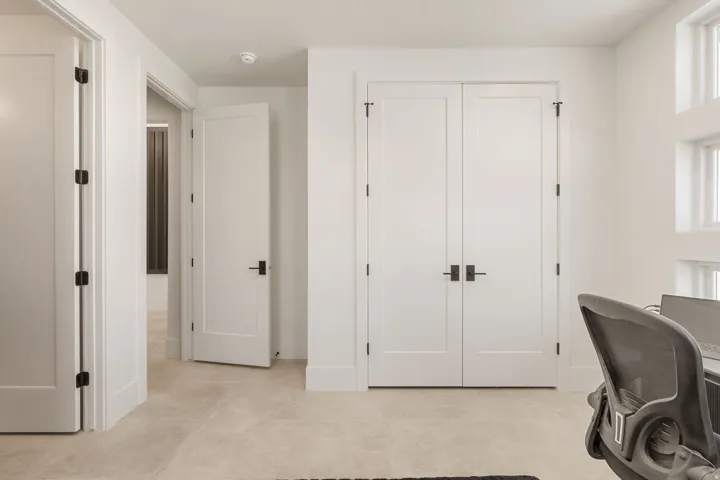 White interior doors with black hardware, light neutral flooring, and white trim