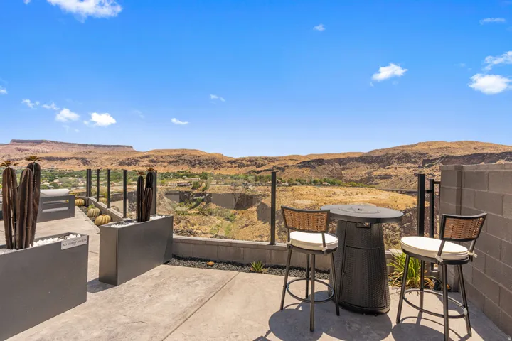 Outdoor patio with a glass railing system showcasing panoramic desert and canyon scenery